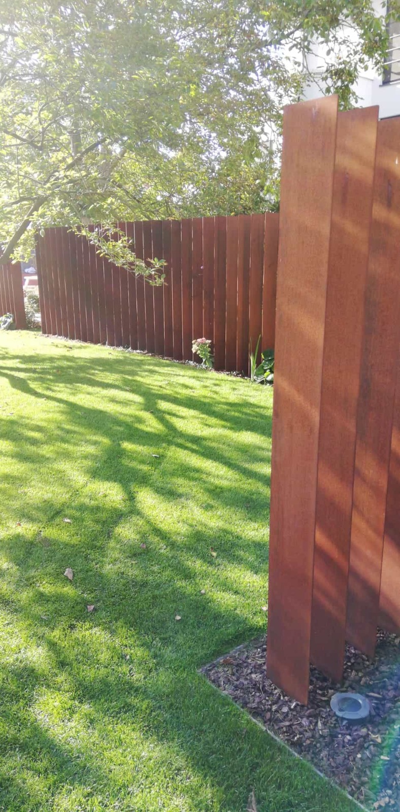 Clôture en acier Corten dans un jardin, lames verticales